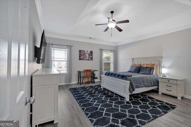bedroom featuring baseboards, multiple windows, ornamental molding, and wood finished floors