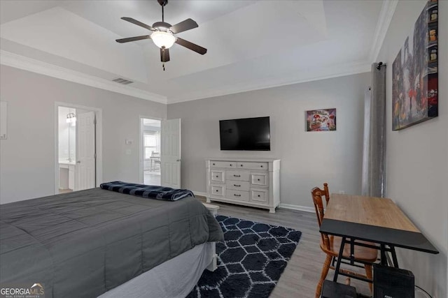 bedroom with baseboards, visible vents, wood finished floors, a tray ceiling, and crown molding
