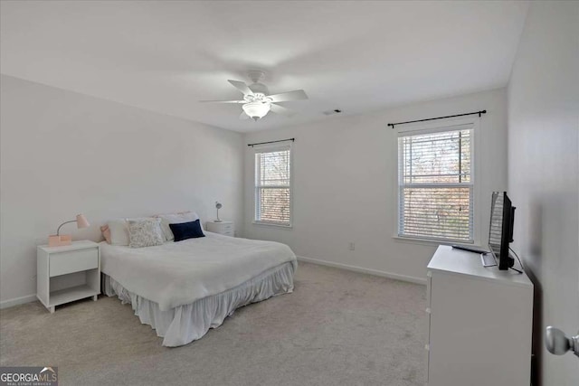 bedroom featuring multiple windows, baseboards, and light colored carpet