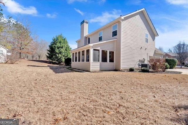 rear view of house featuring central AC, a chimney, and a sunroom