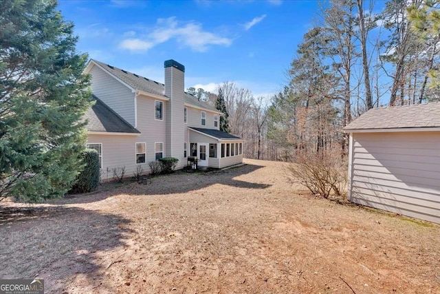 view of side of property featuring a chimney and a sunroom