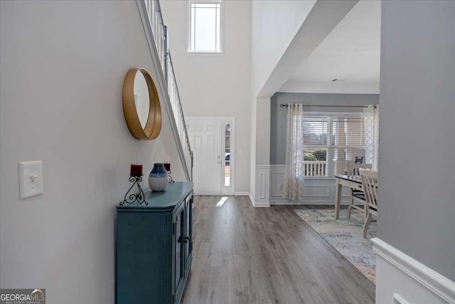 foyer entrance with a wainscoted wall, a decorative wall, and wood finished floors