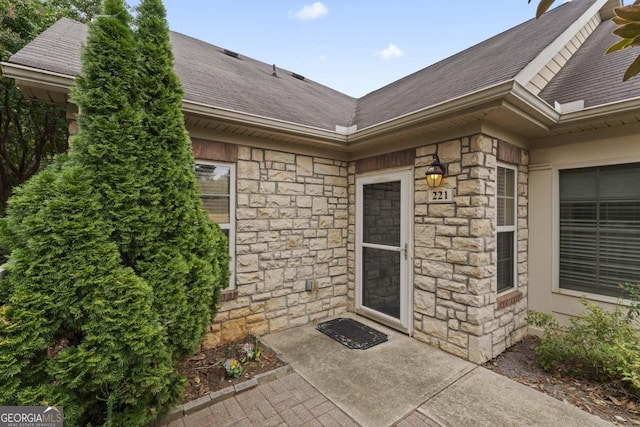 property entrance with stone siding and roof with shingles