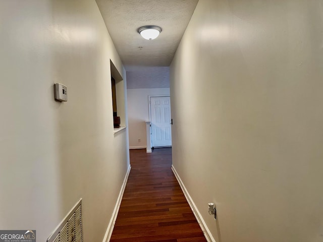 hallway featuring a textured ceiling and dark hardwood / wood-style floors