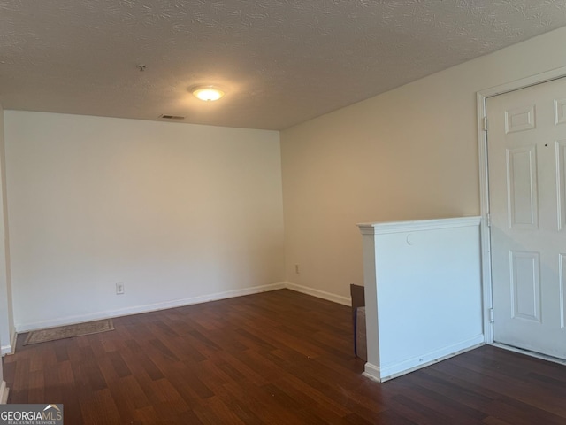 empty room featuring a textured ceiling and dark hardwood / wood-style floors