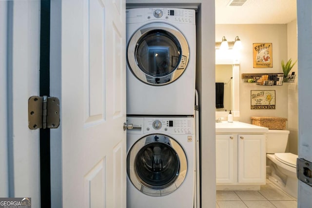 washroom with light tile patterned floors and stacked washer / drying machine