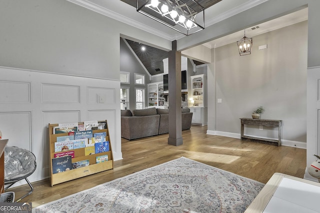 entryway with high vaulted ceiling, hardwood / wood-style floors, crown molding, and an inviting chandelier