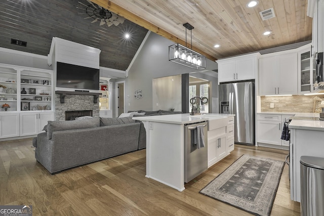 kitchen featuring an island with sink, white cabinetry, stainless steel appliances, and wood ceiling