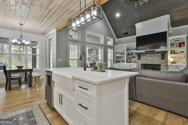 kitchen with hanging light fixtures, white cabinets, wooden ceiling, sink, and a kitchen island with sink