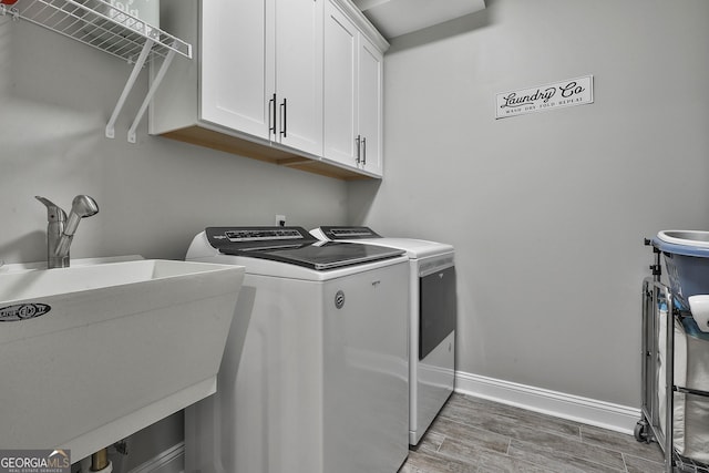 laundry area featuring cabinets, washer and clothes dryer, dark hardwood / wood-style floors, and sink