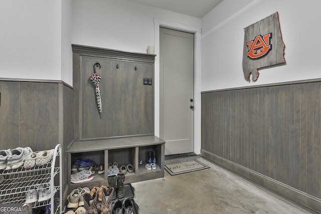 mudroom featuring concrete floors and wood walls