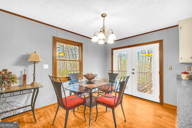 dining area featuring light hardwood / wood-style flooring, crown molding, french doors, and a wealth of natural light