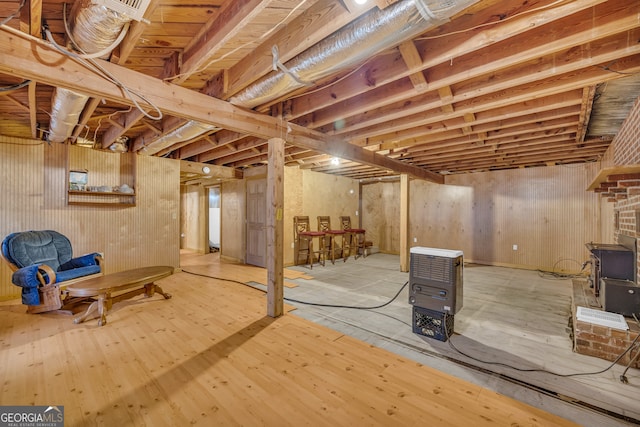 basement featuring a wood stove and light hardwood / wood-style floors