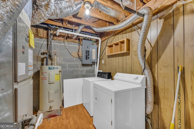 laundry area featuring water heater, electric panel, light hardwood / wood-style floors, separate washer and dryer, and heating unit