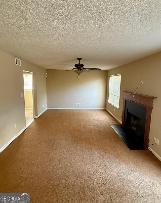 unfurnished living room featuring ceiling fan, carpet, and a textured ceiling