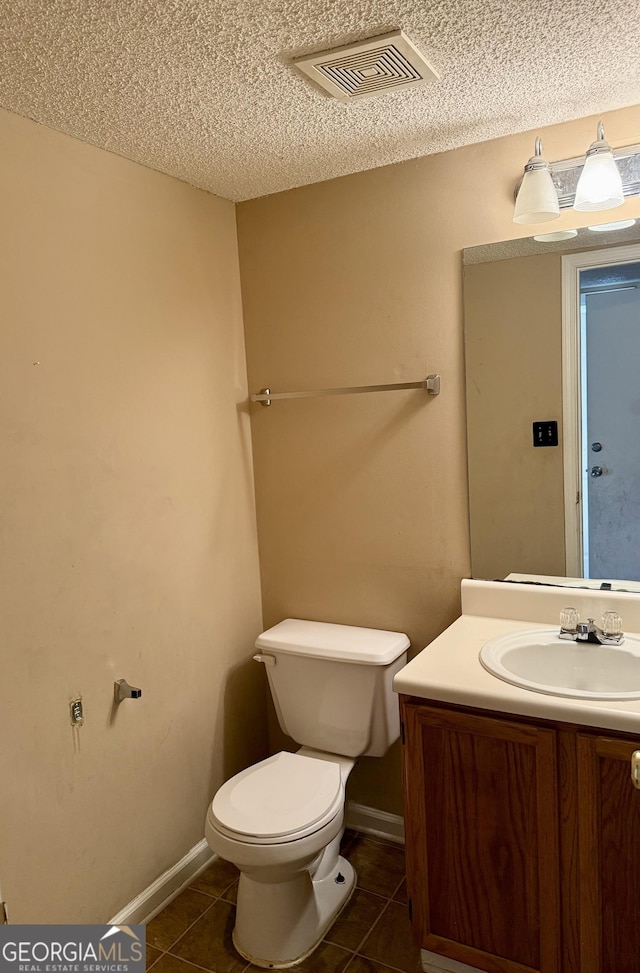 bathroom with vanity, a textured ceiling, tile patterned flooring, and toilet