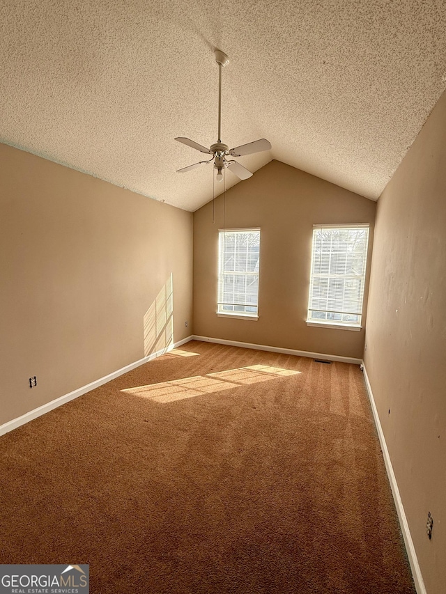 empty room with vaulted ceiling, carpet flooring, and a textured ceiling