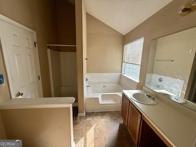 bathroom featuring a tub to relax in, tile patterned flooring, vaulted ceiling, a textured ceiling, and vanity