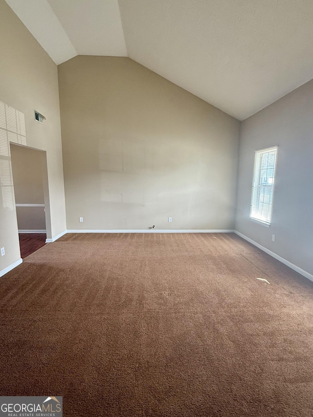 carpeted spare room featuring high vaulted ceiling