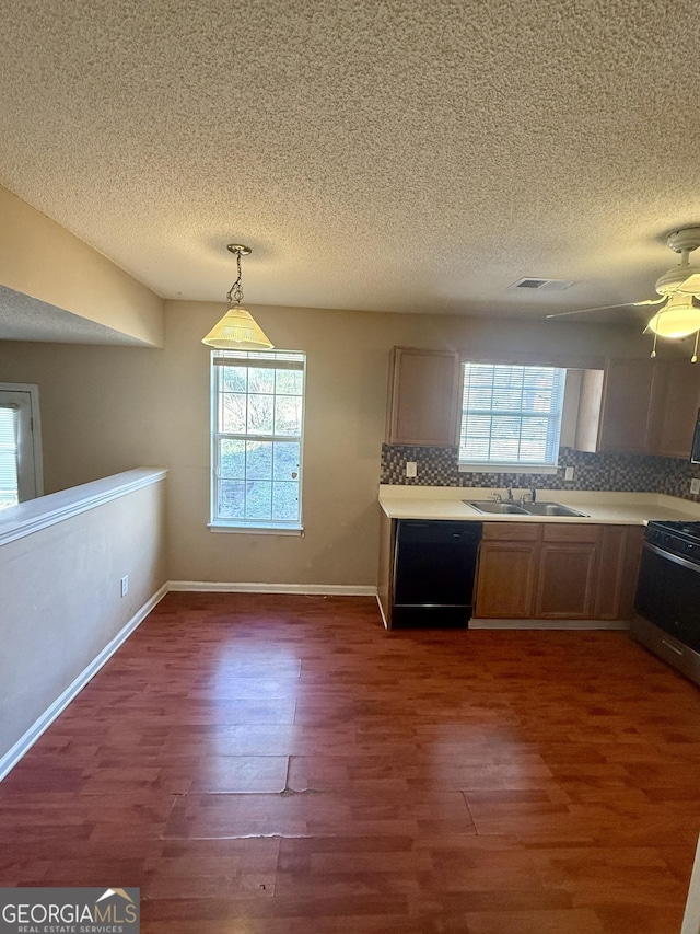 kitchen with pendant lighting, backsplash, sink, black dishwasher, and dark hardwood / wood-style floors