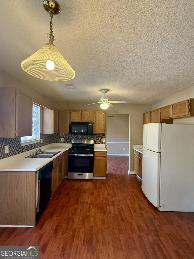 kitchen with black appliances, sink, tasteful backsplash, dark wood-type flooring, and pendant lighting