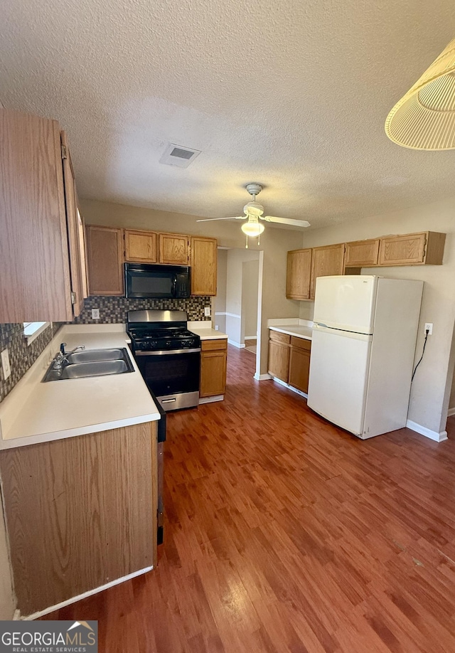 kitchen featuring white refrigerator, sink, dark wood-type flooring, and gas range