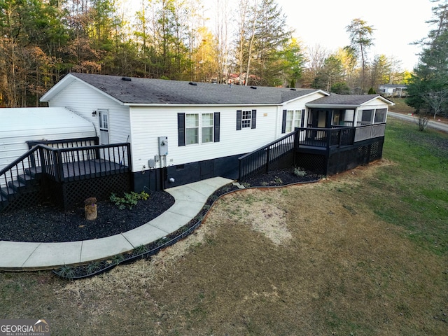 rear view of property featuring a yard, a wooden deck, and a sunroom