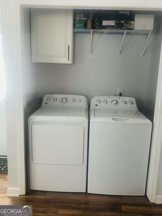 laundry area featuring cabinets, dark hardwood / wood-style flooring, and washing machine and clothes dryer