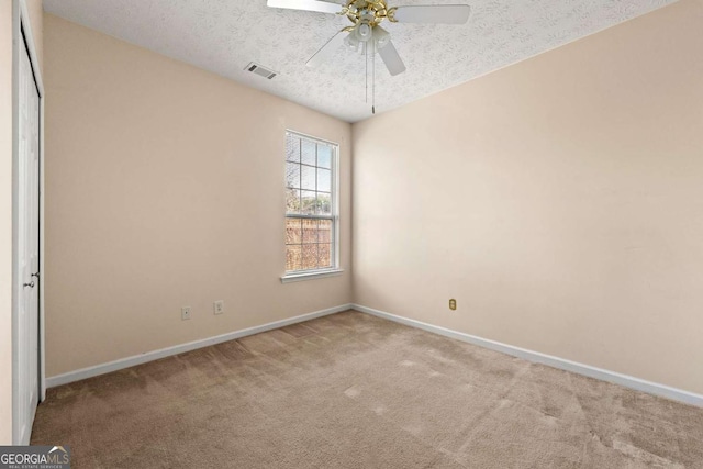 carpeted spare room with a textured ceiling and ceiling fan