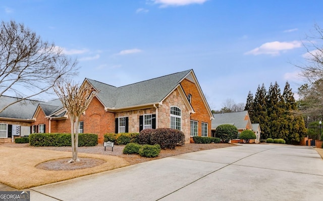 view of front of home featuring brick siding, stone siding, and roof with shingles