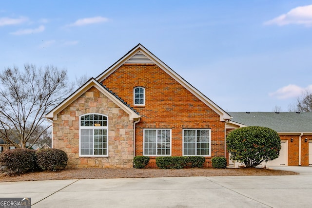 view of front of property featuring stone siding, brick siding, and concrete driveway