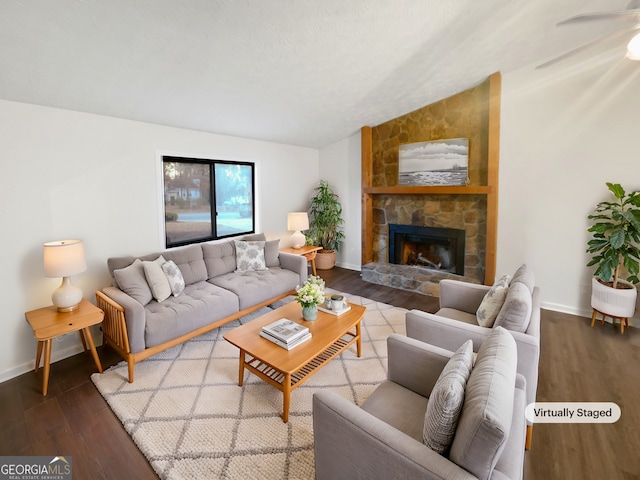 living area featuring lofted ceiling, baseboards, wood finished floors, and a stone fireplace