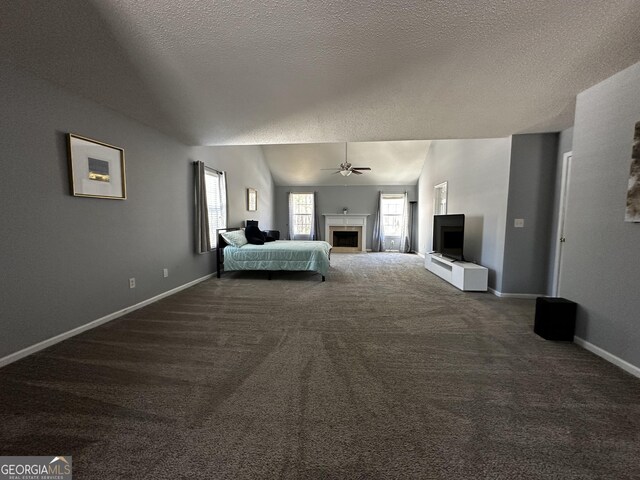 unfurnished bedroom with dark carpet, ceiling fan, a textured ceiling, and lofted ceiling