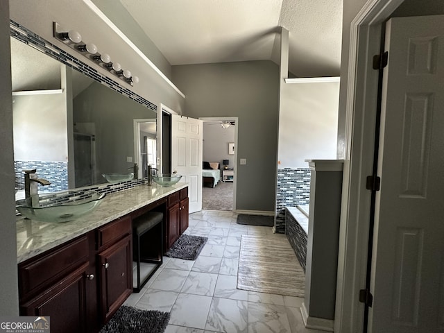 bathroom with lofted ceiling, a bath, ceiling fan, a textured ceiling, and vanity