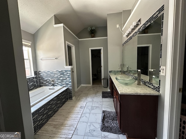 bathroom with vaulted ceiling, vanity, and a relaxing tiled tub