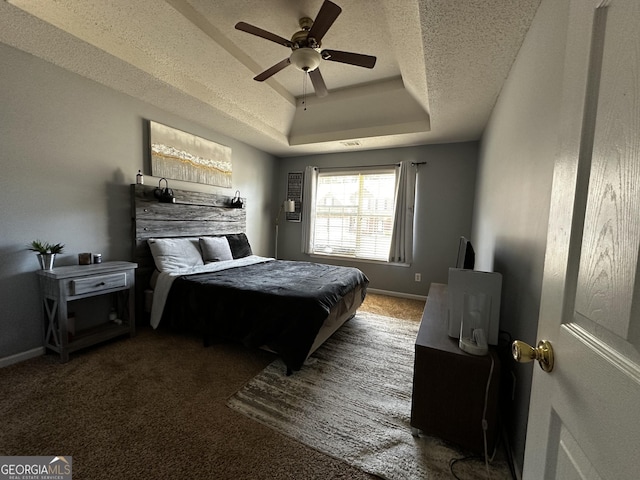 carpeted bedroom featuring ceiling fan, a raised ceiling, and a textured ceiling