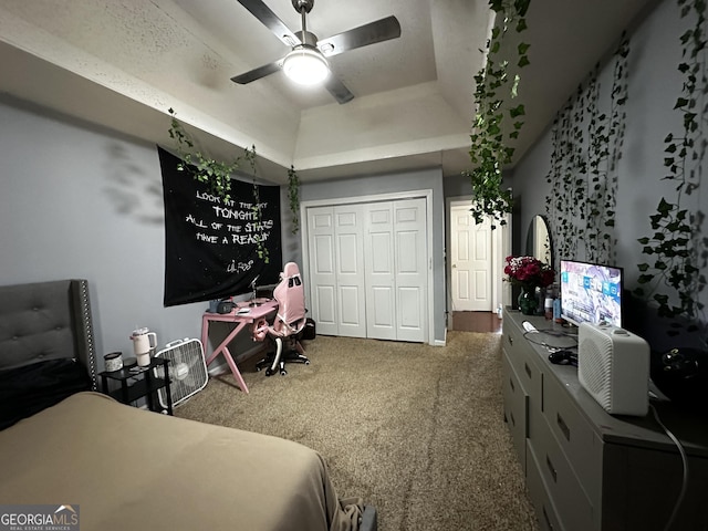 bedroom featuring a tray ceiling, ceiling fan, carpet, and a closet