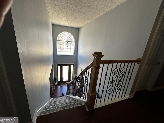stairway featuring a high ceiling and a textured ceiling