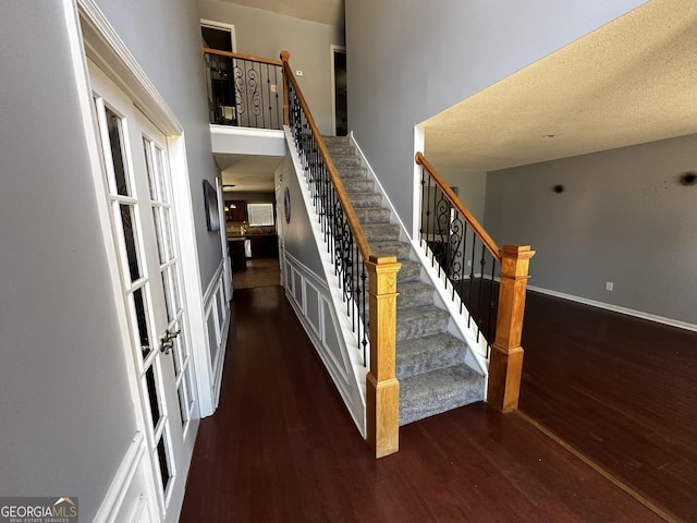 staircase featuring hardwood / wood-style floors, a high ceiling, and a textured ceiling