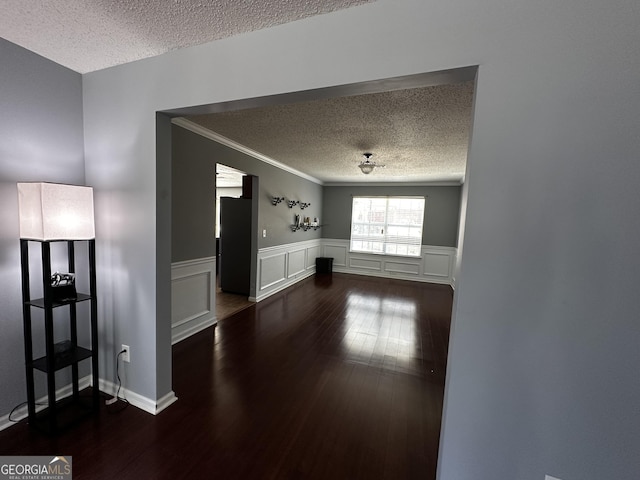 unfurnished living room with a textured ceiling, ornamental molding, and dark hardwood / wood-style flooring