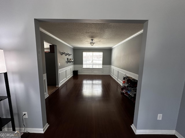 unfurnished dining area featuring a textured ceiling, dark wood-type flooring, and ornamental molding