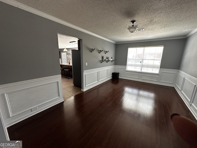 unfurnished room featuring crown molding, wood-type flooring, and a textured ceiling