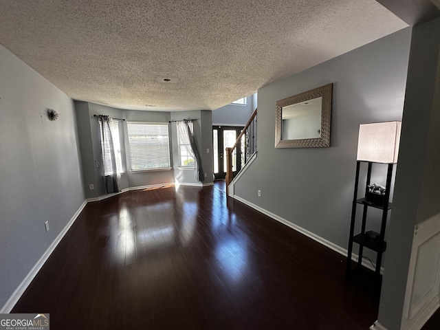 unfurnished living room with dark hardwood / wood-style flooring and a textured ceiling