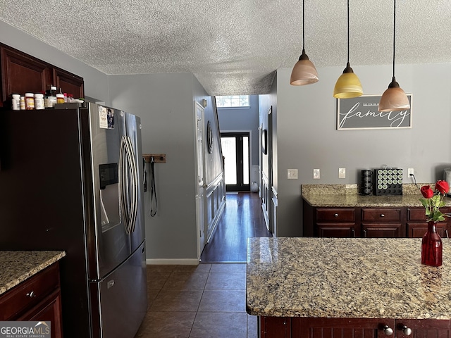 kitchen with dark tile patterned flooring, light stone countertops, hanging light fixtures, and stainless steel refrigerator with ice dispenser