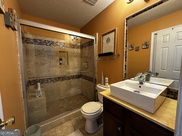 bathroom featuring vanity, a textured ceiling, a shower with shower door, and toilet