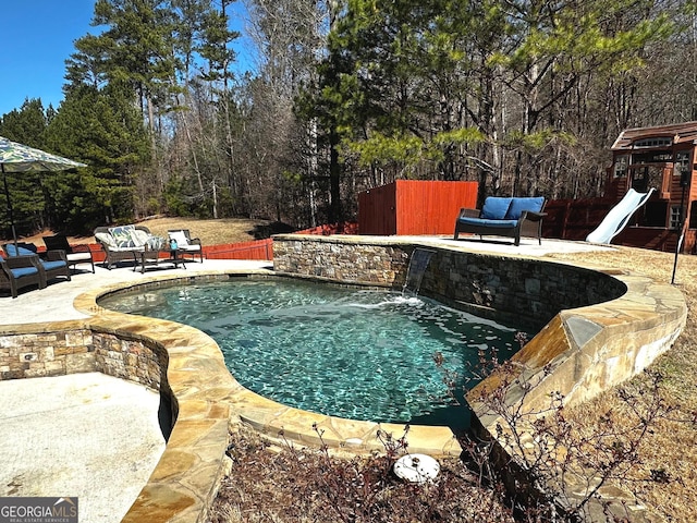 view of pool with an outdoor living space, pool water feature, a playground, and a patio area