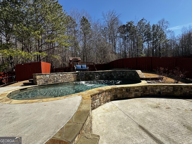 view of swimming pool with pool water feature and a patio area