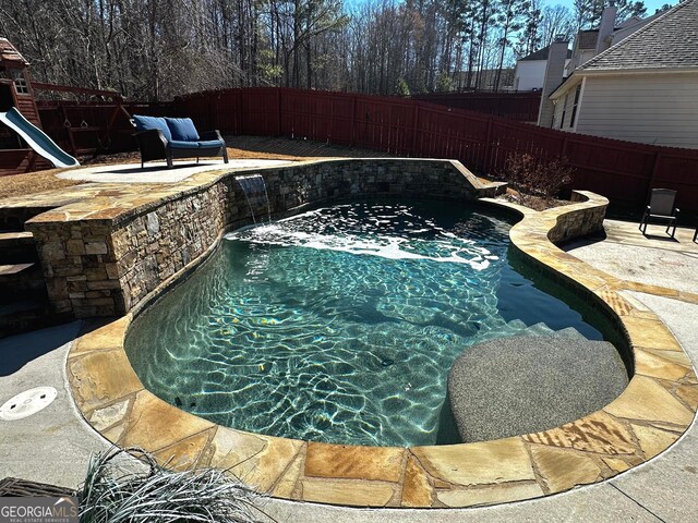 view of swimming pool with a patio, a playground, and pool water feature