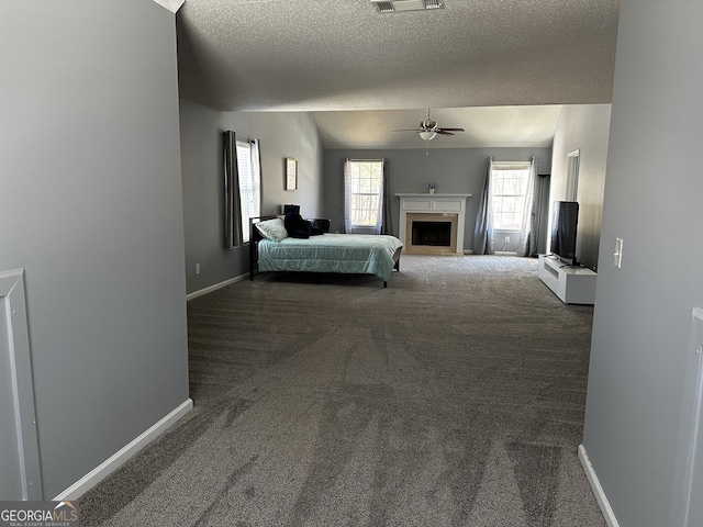 unfurnished bedroom with a textured ceiling, lofted ceiling, dark colored carpet, and ceiling fan