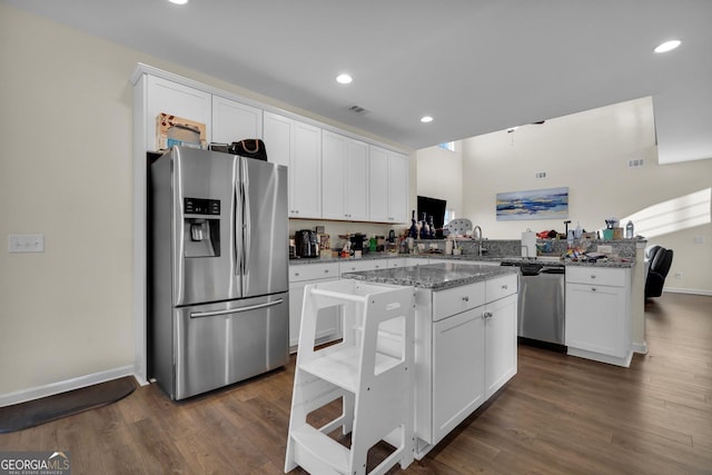 kitchen featuring a kitchen island, appliances with stainless steel finishes, white cabinets, and light stone counters